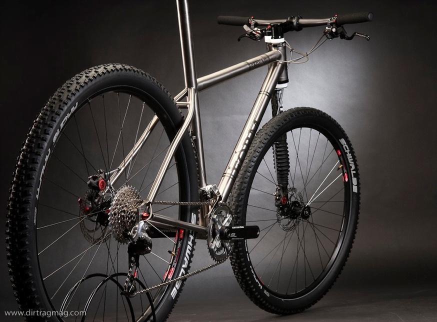 Form Cycles: A sleek, modern mountain bike featuring a titanium frame, showcasing large, rugged tires and a high-quality drivetrain. The bike is positioned against a dark background, highlighting its design and components, including detailed gears and brake systems.