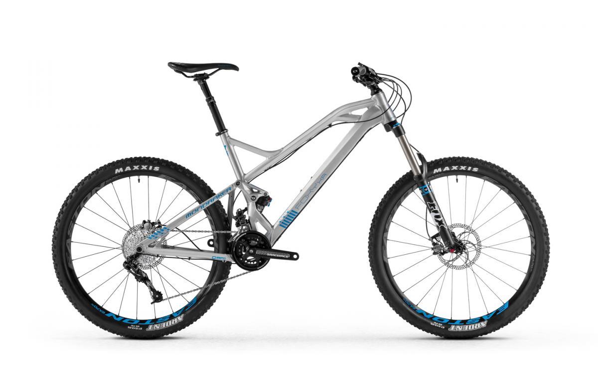 Mondraker Foxy XR: A modern mountain bike with a sleek gray frame and blue accents, featuring wide tires equipped with Maxxis branding, a front suspension fork, and a range of gears. The bike is positioned on a plain white background, showcasing its design and components.