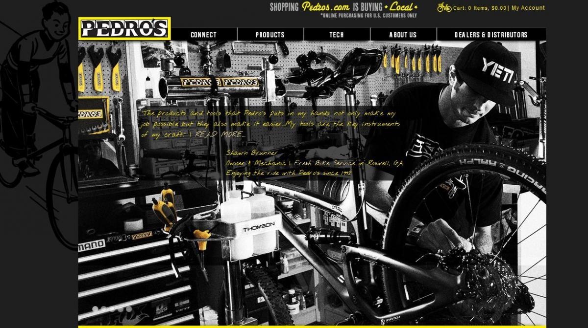 Image of a bike mechanic working in a well-equipped workshop. The mechanic is focused on adjusting a bicycle