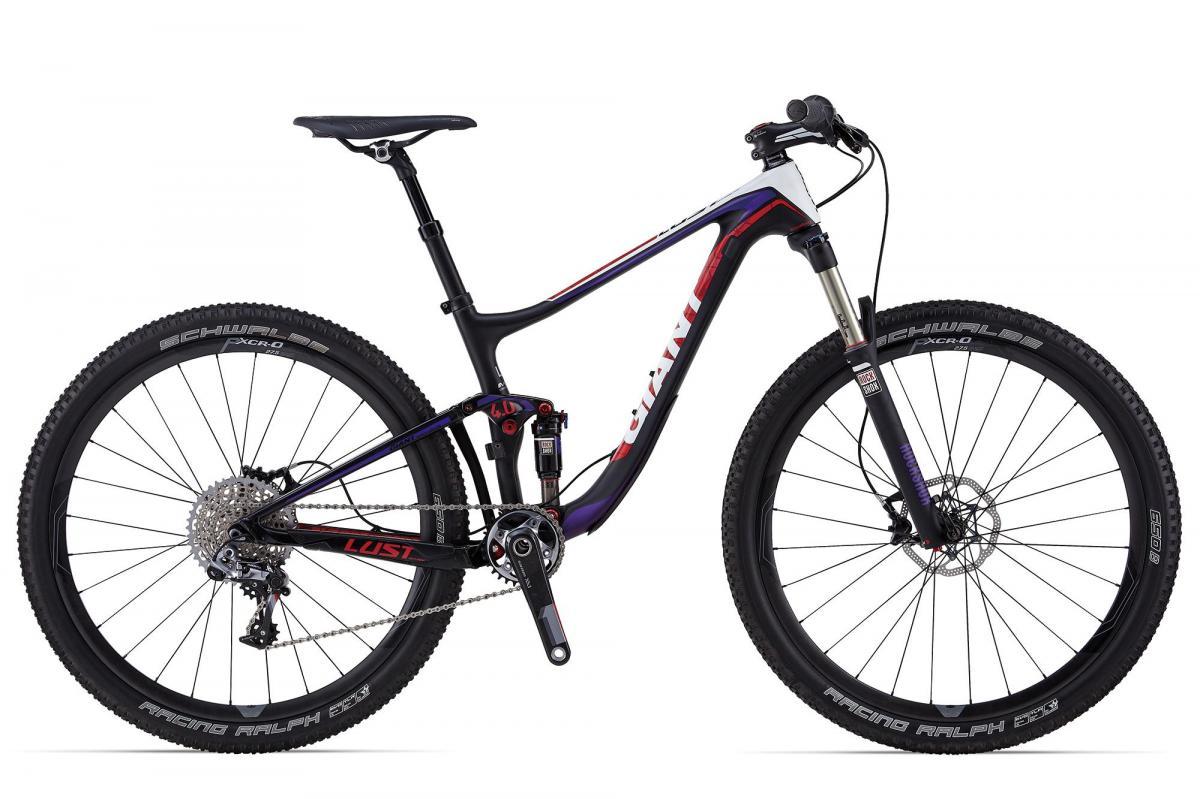 Giant Lust Advanced 0: A modern mountain bike with a sleek black, white, and purple frame, featuring front suspension, disc brakes, and knobby tires designed for off-road terrain. The bike prominently displays the brand name on the frame.