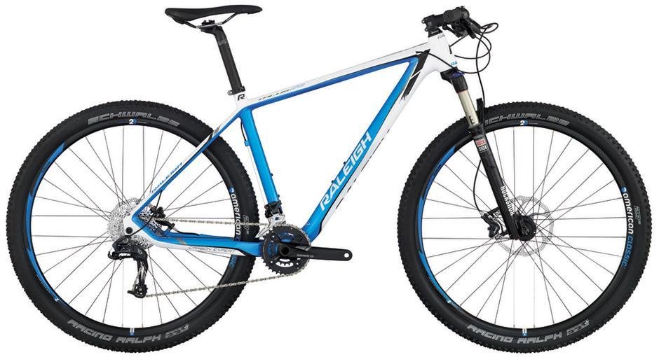 Raleigh Talus 29 Carbon Expert: A sleek mountain bike featuring a lightweight frame with a white and blue color scheme, front suspension fork, and knobby tires suitable for off-road riding.