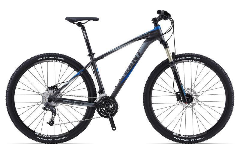Giant Talon 29er 1: A modern mountain bike featuring a sleek gray and blue frame, equipped with sturdy wheels and Schwalbe tires. The bike showcases a front suspension fork, multiple gears, and disc brakes, designed for off-road cycling and outdoor adventures.
