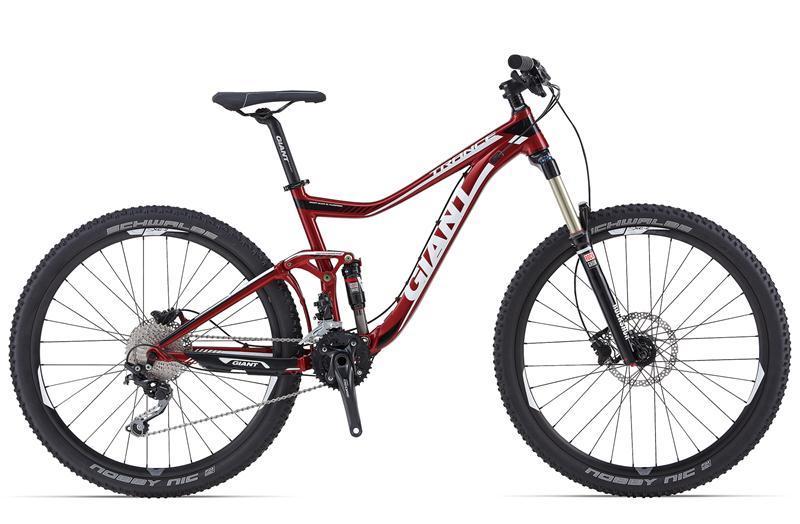Giant Trance 27.5 3: A red mountain bike with a sleek frame and wide tires, featuring front suspension, disc brakes, and a modern design. The bike is positioned against a clean white background, showcasing its details and components.