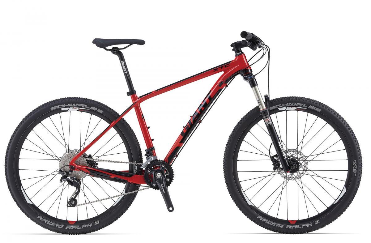 Giant XTC 27.5 2: A sleek red and black mountain bike featuring a lightweight aluminum frame, front suspension fork, and high-performance tires from Schwalbe. The bike is positioned to display its modern design, with a focus on the drivetrain and gear system.
