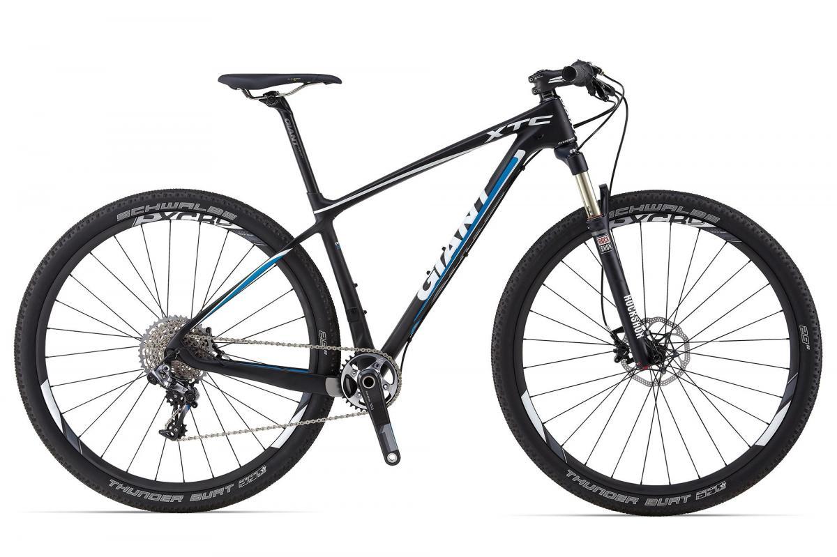 Giant XTC Advanced SL 29er 0: A sleek black mountain bike with blue accents, featuring large tires, a front suspension fork, and a detailed gear system. The bike is designed for off-road riding and showcases brands like Giant and Schwalbe on its components.