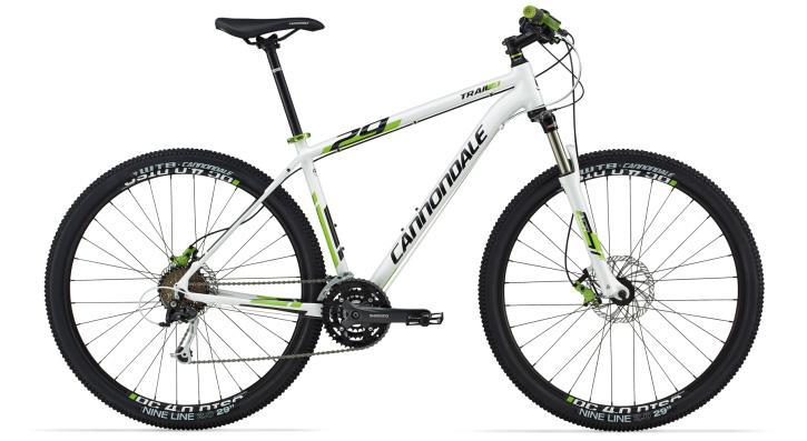 Cannondale Trail 29 4: Alt text: A white Cannondale Trail mountain bike with green accents, featuring thick tires, front suspension, and a standard bike saddle, standing upright against a plain background.