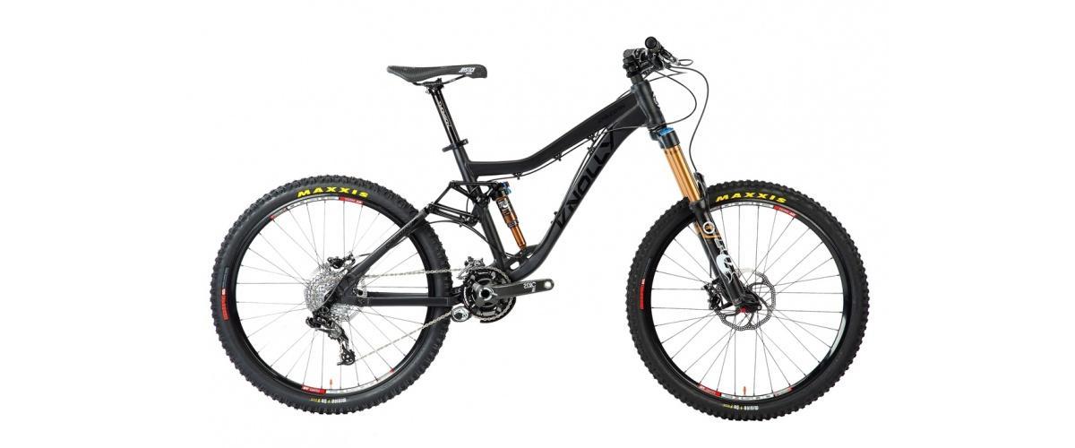 Knolly Chilcotin: A black mountain bike with front suspension, wide tires, and a sleek design, positioned against a plain background. The bike features gold-colored fork components and is branded with Maxxis tires.