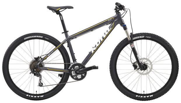 Kona BLAST 27.5: A modern mountain bike featuring a grey frame with yellow accents, sturdy wheels with thick tires, front suspension, and disc brakes.