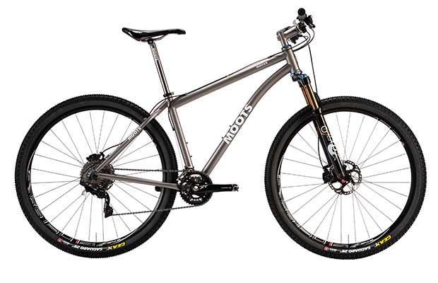 Moots MOOTO X 2014: A high-quality, silver titanium mountain bike with a lightweight frame, featuring front suspension, disc brakes, and rugged tires, designed for off-road cycling.