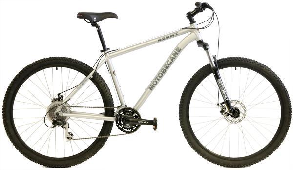 Motobecane 429HT: A silver mountain bike with wide tires, featuring a sturdy frame, a front suspension fork, and disc brakes. The bike is designed for rugged terrain, showcasing gears and a comfortable seat.