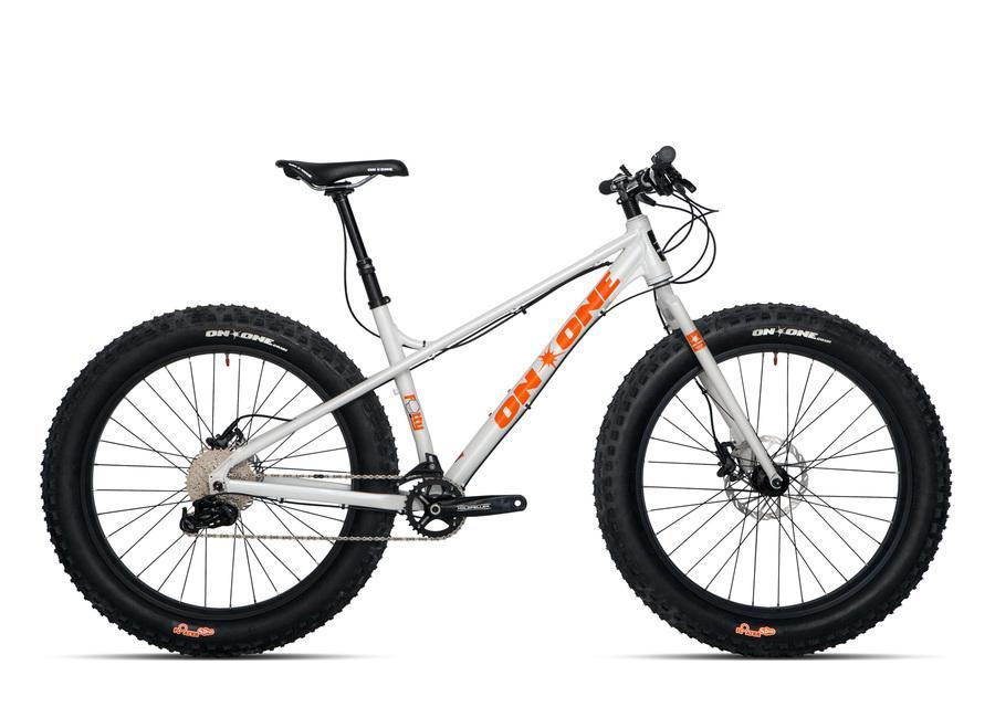 On-One Fatty: An off-road fat tire bike with a lightweight silver frame and wide black tires, featuring orange accents and the brand name "ON-ONE" visible on the frame and wheels. The bike is designed for rugged terrains and has a simple, sturdy design suitable for outdoor adventures.