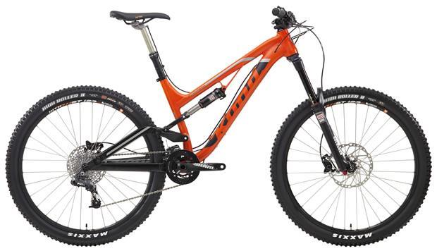 Kona Process 153: A mountain bike with a vibrant orange frame, featuring front suspension, wide tires, and disk brakes. The bike has a sleek design, showcasing a modern build suitable for off-road riding.