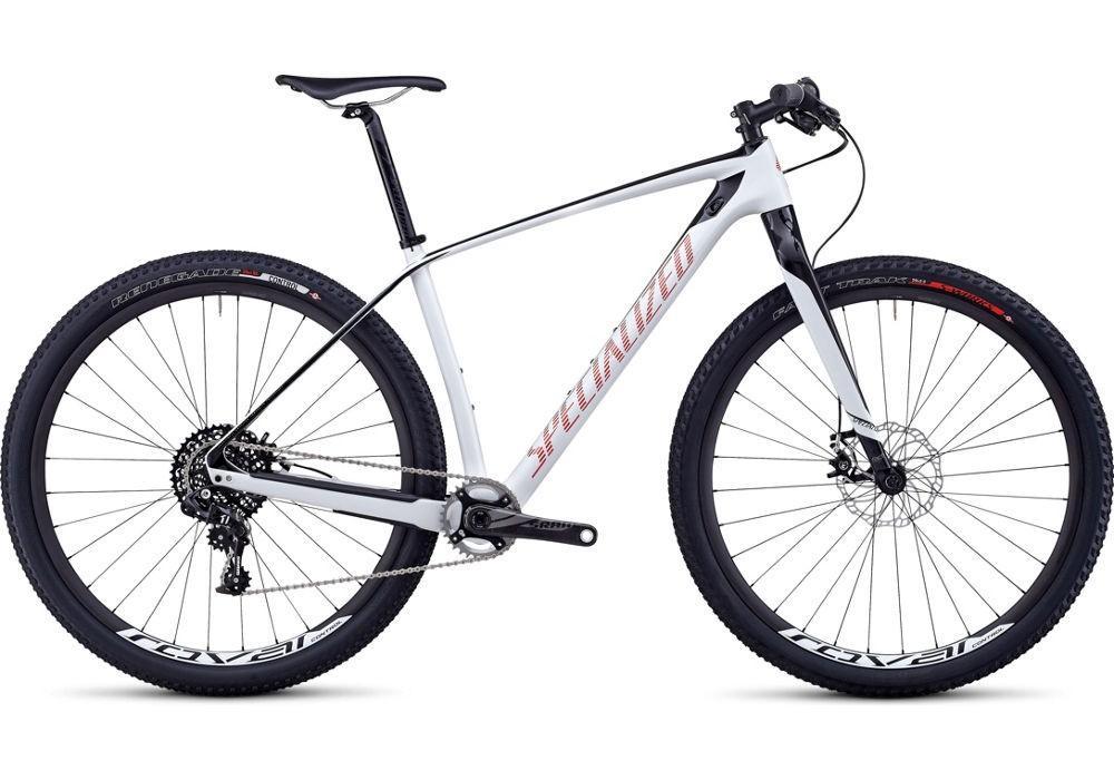 Specialized STUMPJUMPER EXPERT CARBON HT: A modern mountain bike with a sleek white frame and red accents, featuring wide tires, a rear derailleur, and disc brakes. The bike is designed for high performance and durability on off-road trails, showcasing a lightweight design and advanced gearing system.