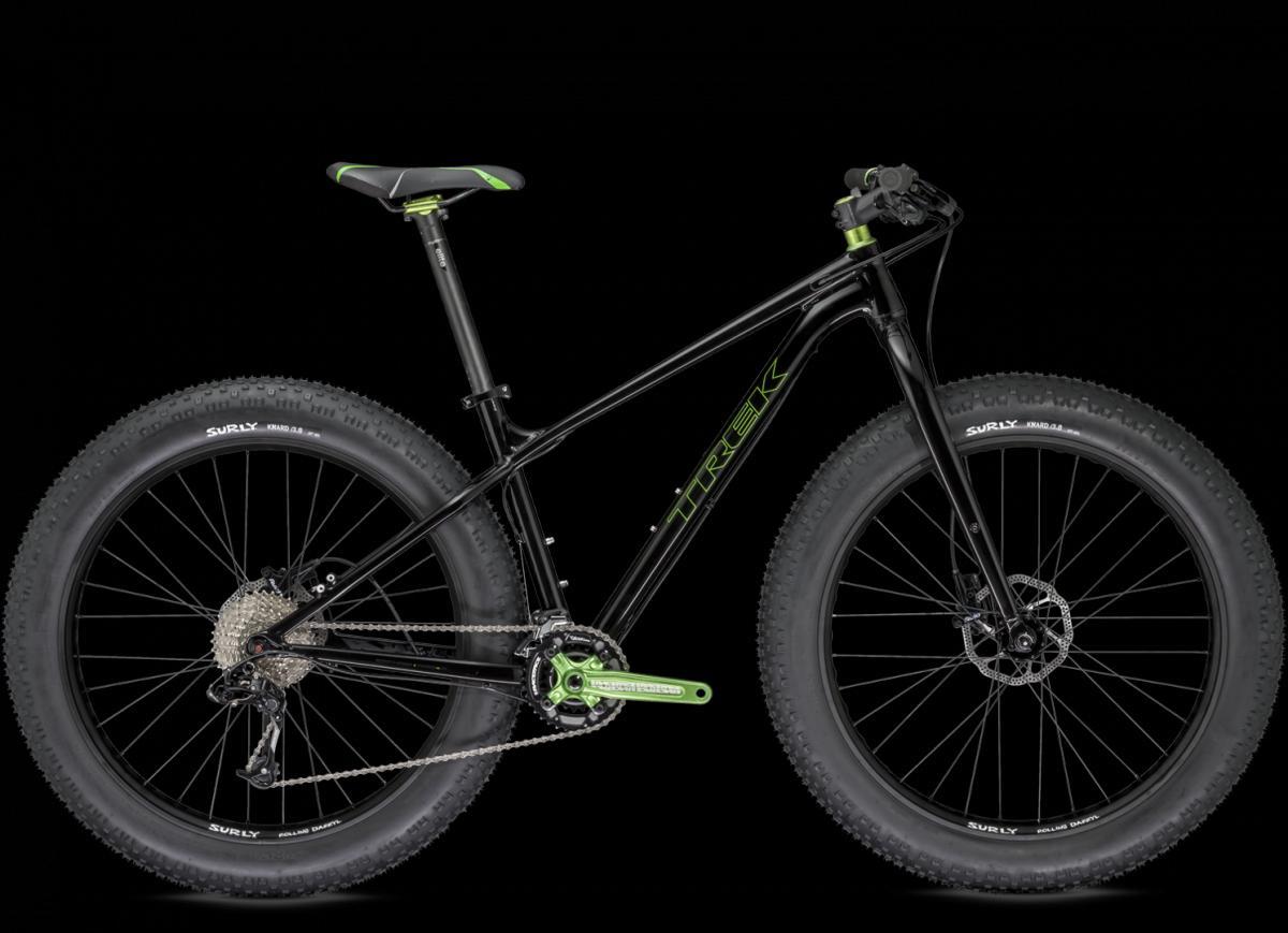 Trek Farley: A black Trek fat bike with vibrant green accents, featuring wide tires and a modern design. The bike showcases a sleek frame, a comfortable saddle, and geared drivetrain components, highlighted against a black background.