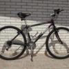 Trek 930: A black mountain bike leaning against a textured gray brick wall, showcasing a sturdy frame and thick tires.