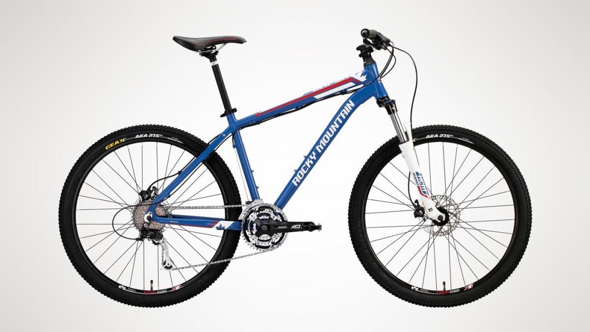 Rocky Mountain Vapor 27.5: Mountain bike with a blue frame and black wheels, featuring disc brakes, a multi-gear drivetrain, and a sleek design for off-road cycling. The image showcases the bike from the side against a white background.