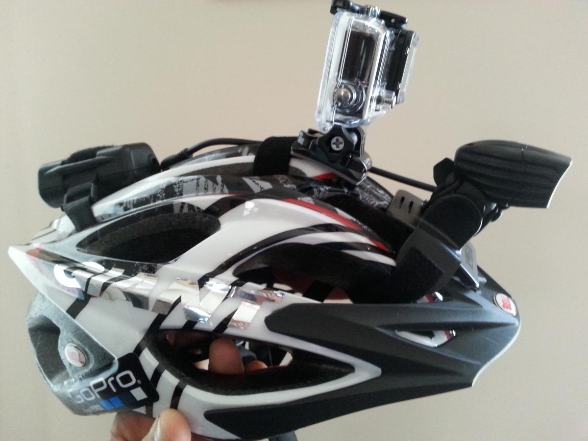 GoPro Hero3: A black and white cycling helmet with a GoPro camera mounted on top, showcasing its streamlined design and ventilation openings.