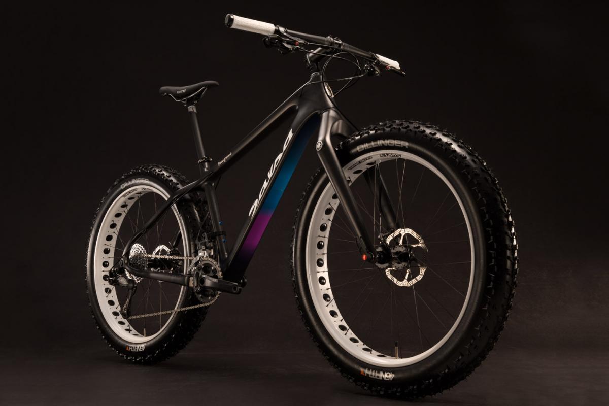 Salsa Beargrease: A sleek black fat tire bike with a gradient design featuring purple and blue accents. The bike is positioned at an angle against a dark background, showcasing its wide tires and modern frame design.