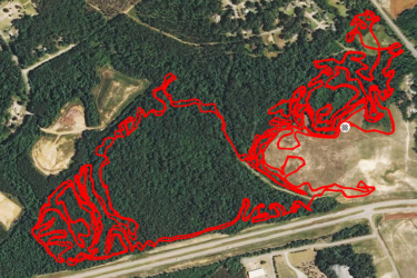 Aerial view of a forested area with a red trail map overlay. The map shows various winding paths through the trees, highlighting routes taken within the wooded landscape. Nearby, there are residential areas and roads visible, providing context to the geographic location. Brown's Creek Nature Park mountain bike trail.