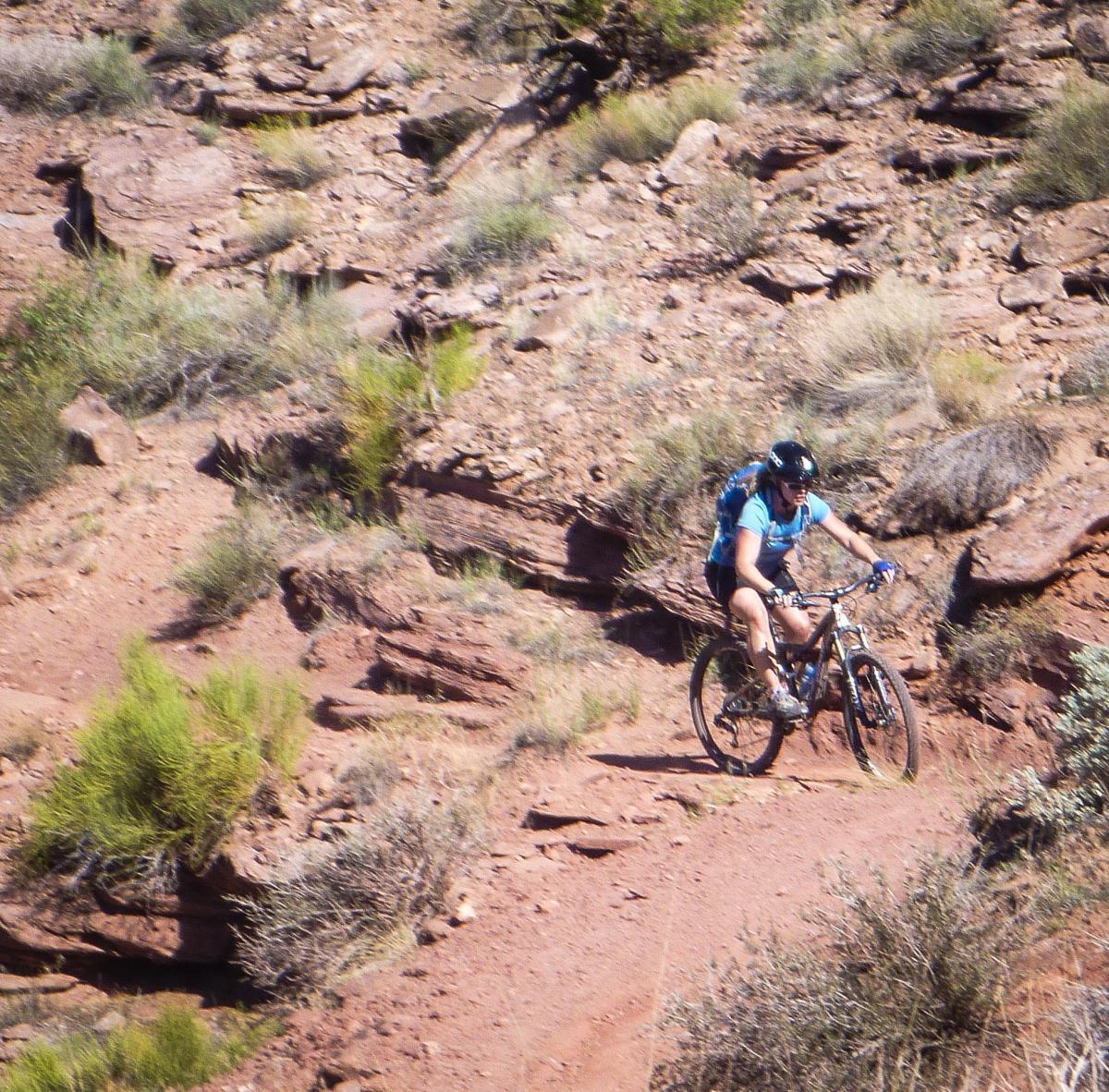 A person riding a mountain bike on a rocky trail surrounded by sparse vegetation in a rugged outdoor landscape. Porcupine Rim mountain bike trail.