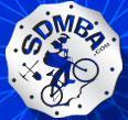 Logo of the San Diego Mountain Biking Association (SDMBA), featuring a blue silhouette of a cyclist in motion against a blue background. The text "SDMBA" is prominently displayed.