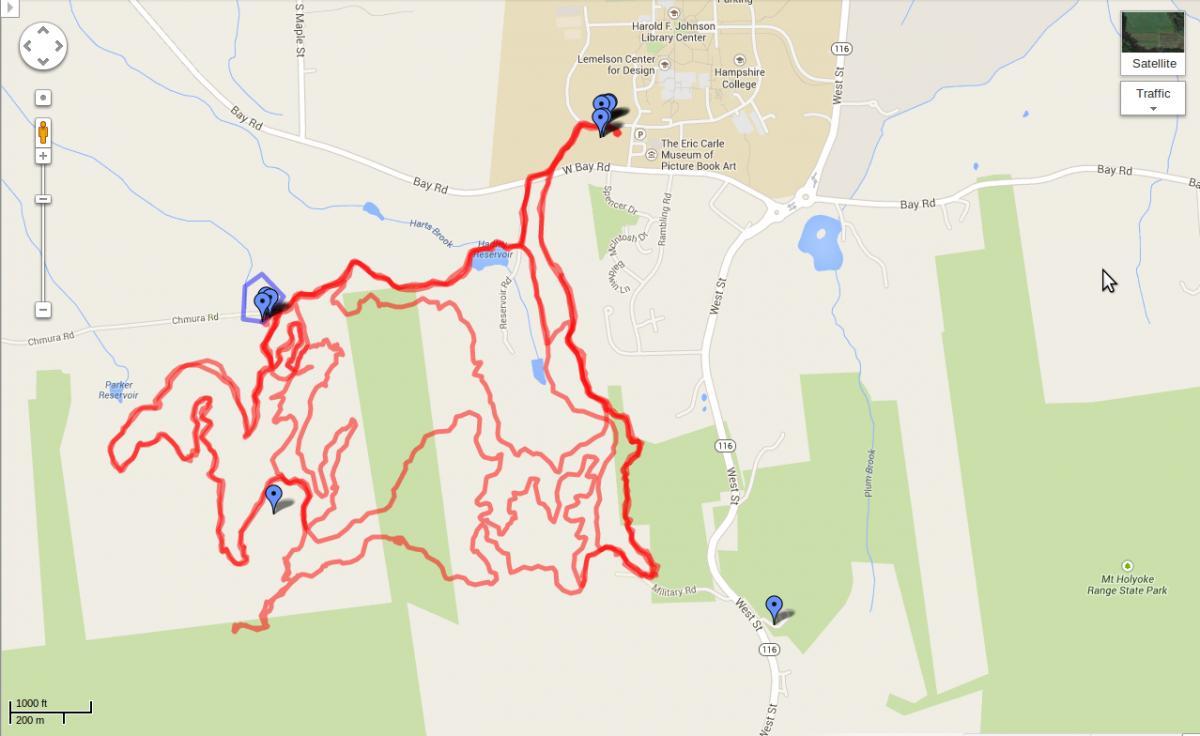 Map showing a marked hiking trail outlined in red, with several waypoints indicated by blue icons. The map is centered around a rural area featuring roads, a reservoir, and wooded regions, along with nearby landmarks such as Hampshire College and Mt. Holyoke Range State Park. Earl