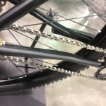 Close-up view of a bicycle's drivetrain, highlighting the chain, rear derailleur, and part of the rear wheel. The photo showcases the intricate details of the bike's mechanical components.