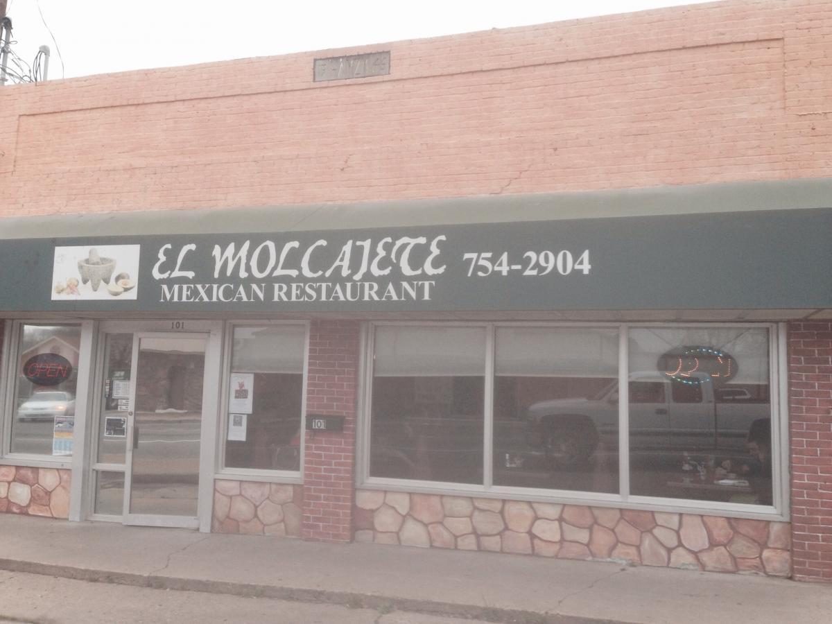 Front view of "El Molcajete," a Mexican restaurant with an open sign in the window. The building has a brick facade, and the sign features the restaurant's name and phone number prominently. Spadra Creek Nature Trail mountain bike trail.