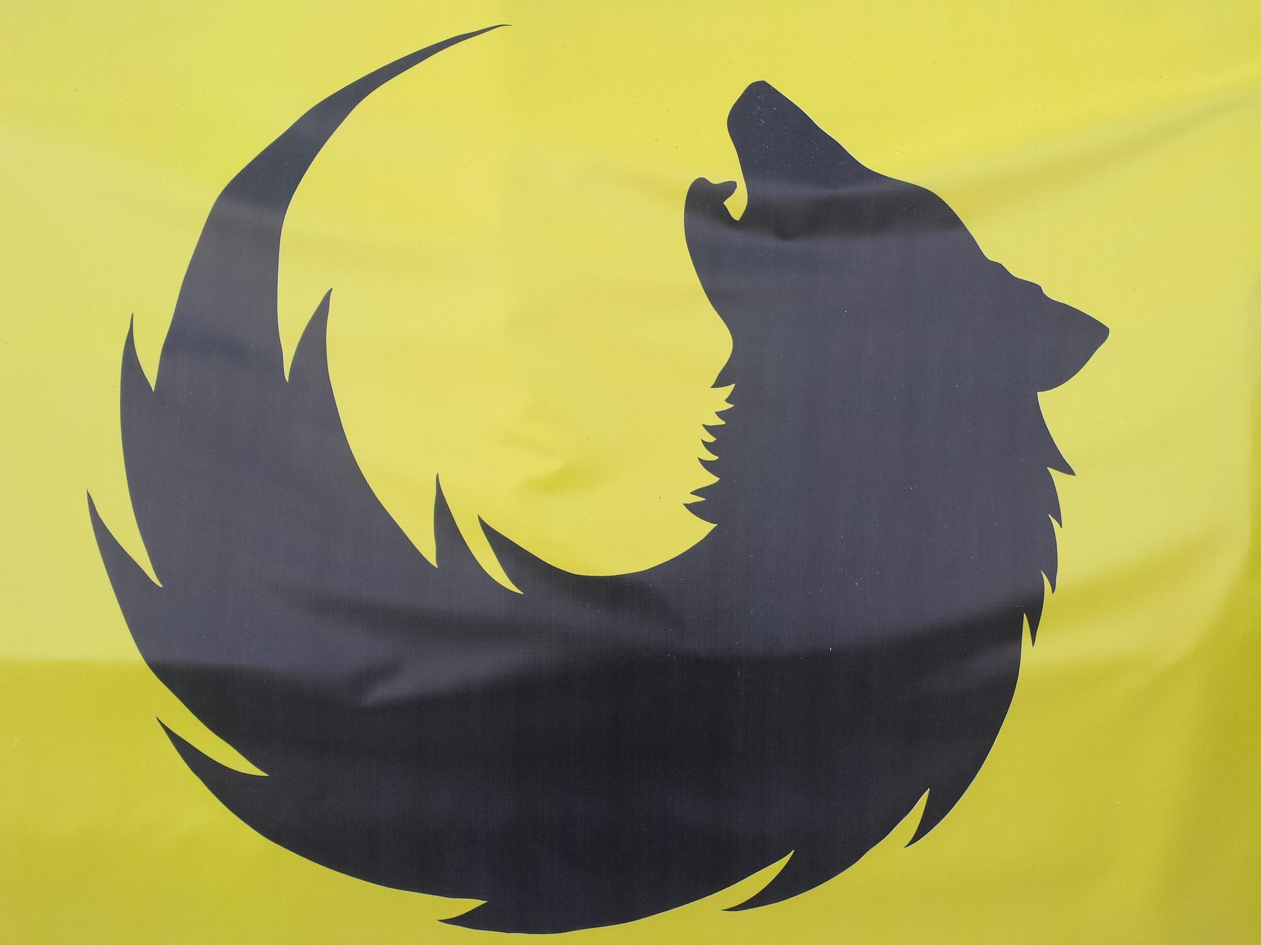 A black silhouette of a howling wolf against a bright yellow background, with the wolf's tail forming a flowing shape.
