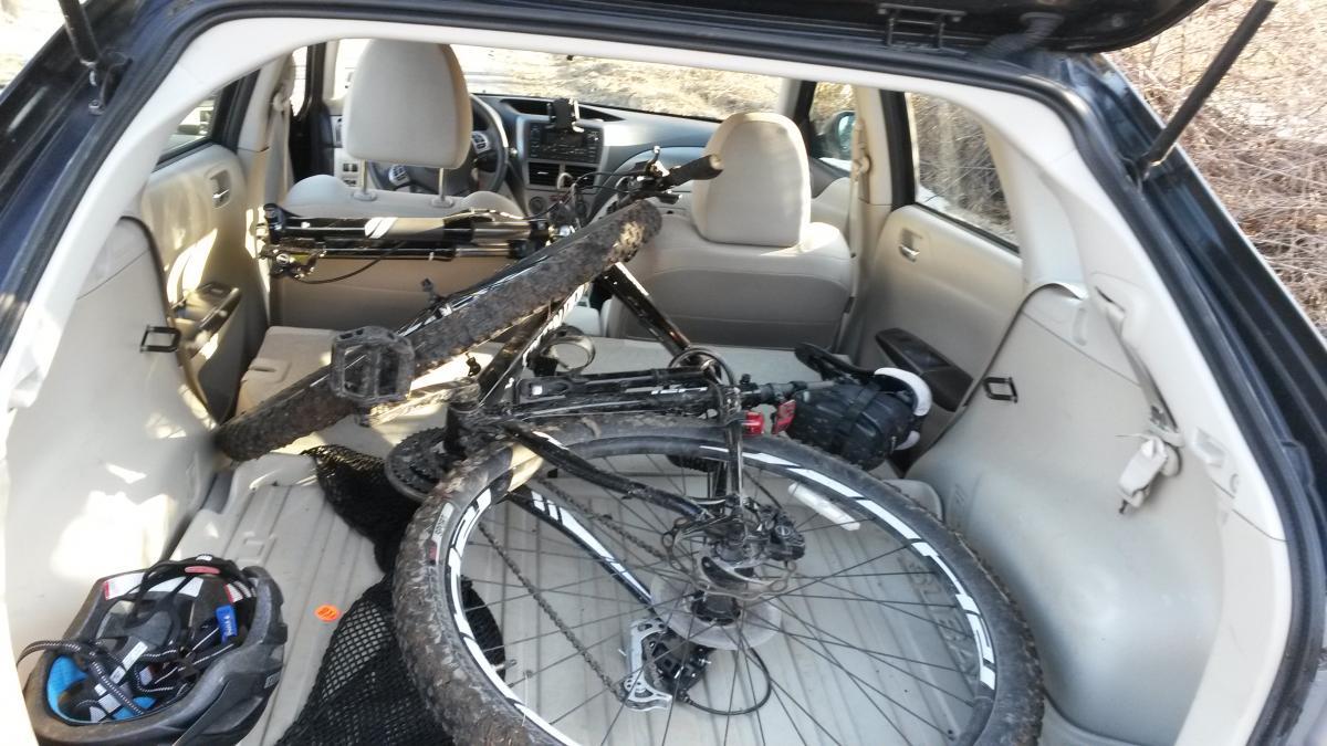 Specialized Rockhopper Comp 29: Alt text: "Interior of a vehicle with a mountain bike partially disassembled, leaning on the back seat. A helmet and other biking gear are visible on the floor."