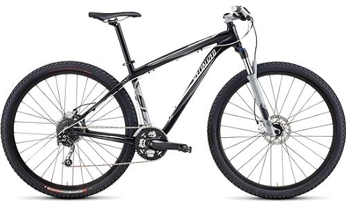 Specialized Rockhopper Expert Disc 29er: A black and silver mountain bike with wide tires, a suspension fork, and a sleek frame design, positioned on a white background.