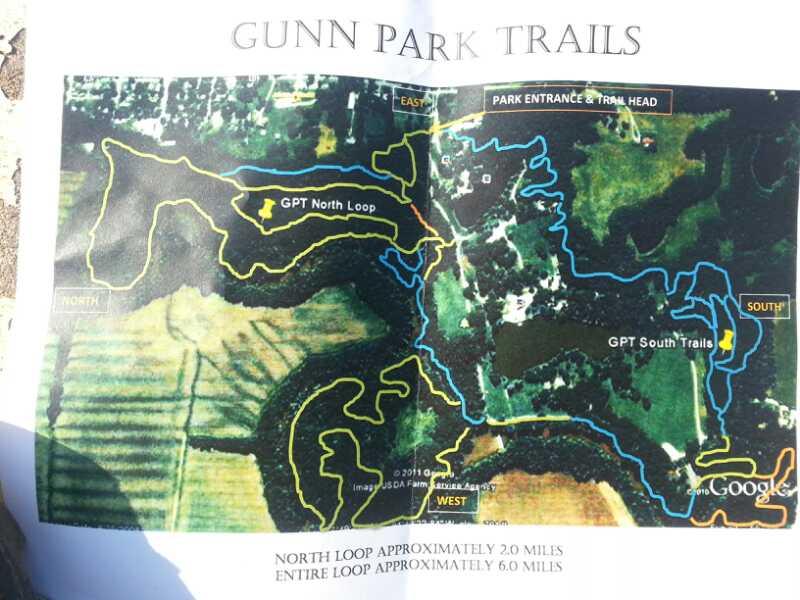 Map of Gunn Park Trails, illustrating the North Loop in yellow and South Trails in blue. The map indicates the park entrance and trailhead, with approximate distances of 2.0 miles for the North Loop and 6.0 miles for the entire loop. Directional markers for North, East, South, and West are also present. Gunn Park Trails mountain bike trail.