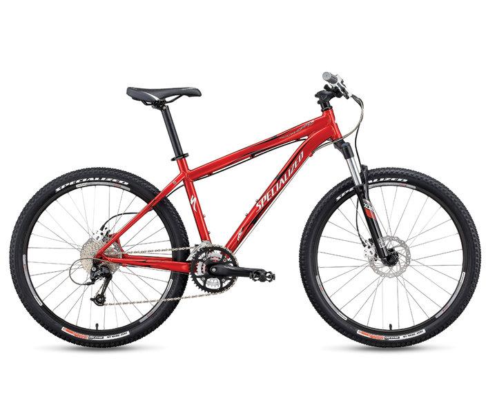 Specialized Rockhopper Comp Disc: Red mountain bike with a sleek design, featuring a lightweight frame, disc brakes, and rugged tires suitable for off-road trails.