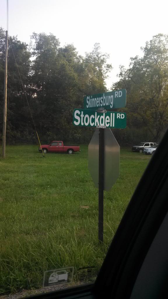 Green street sign at the intersection of Skinnersburg Road and Stockdell Road, with trees and grass in the background. A red pickup truck is parked nearby. Skullbuster mountain bike trail.