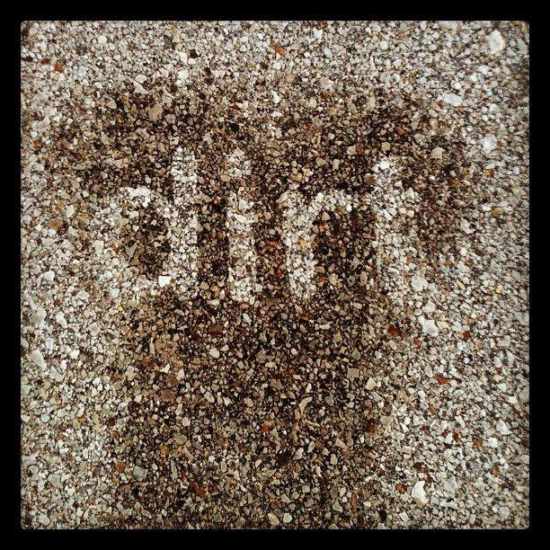 The image features a textured surface covered in small stones and pebbles, with the word "dirt" written in a lighter shade, creating a contrast against the darker background of the gravel.