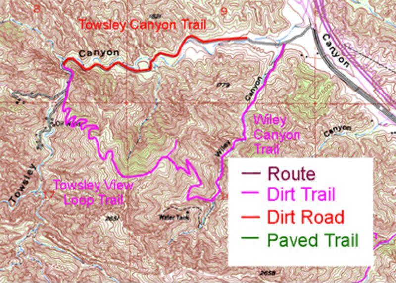 Map showing Towsley Canyon Trail and surrounding trails. The Towsley Canyon Trail is marked in red, while Wifley Canyon Trail is depicted in pink. The Towsley View Loop Trail is represented in purple. The legend indicates the trail types, differentiating between dirt trails, dirt roads, and paved trails. Topographic lines illustrate the hilly terrain of the area. Towsley Canyon mountain bike trail.