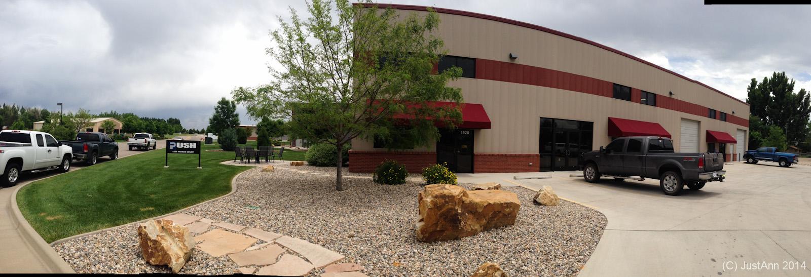A panoramic view of a commercial building featuring a red and beige exterior. In the foreground, there