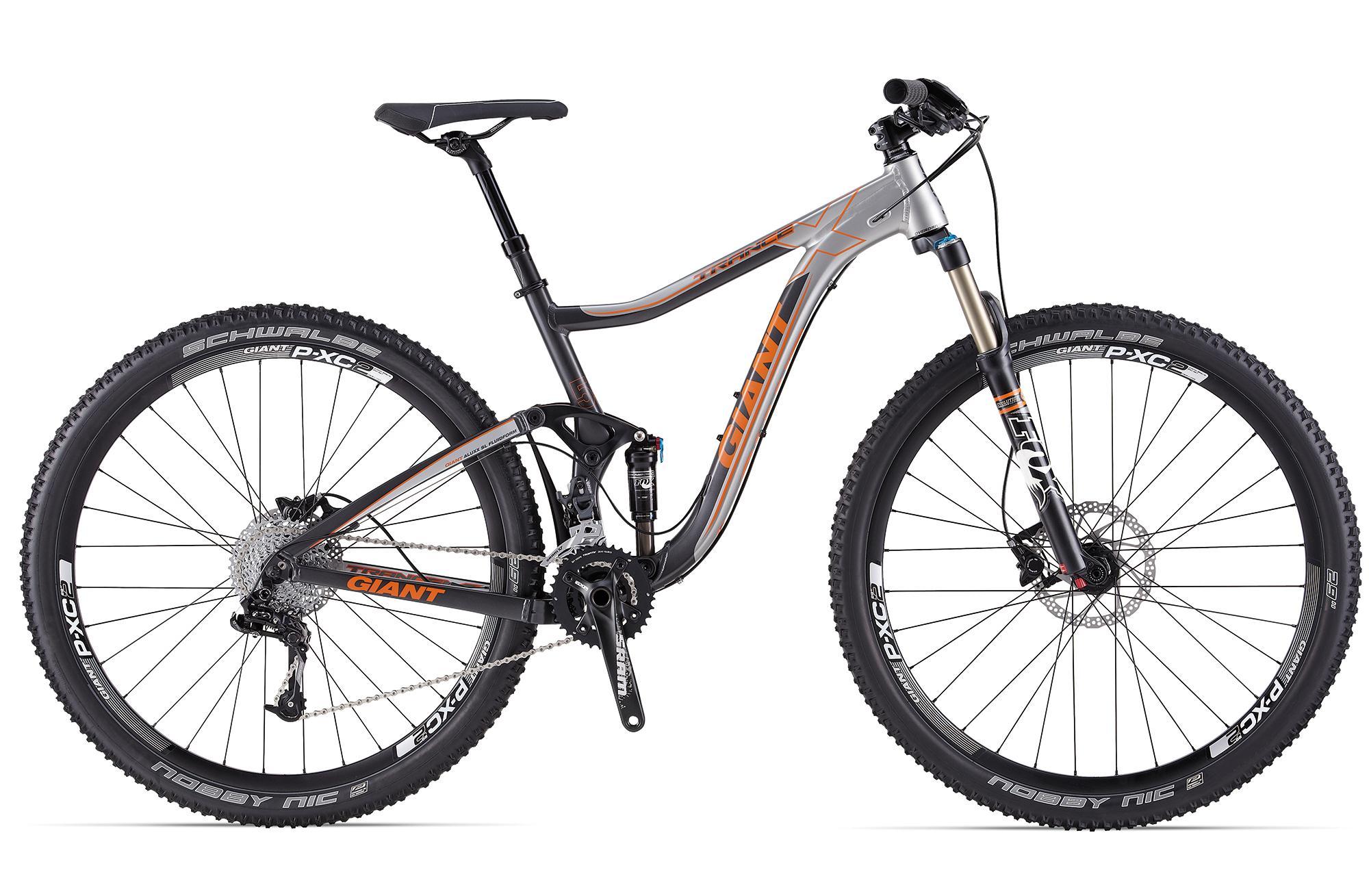 Giant Trance X 29er 1: A modern mountain bike featuring a sleek gray and orange design, equipped with wide tires, a double suspension system, and high-performance components. The bike is positioned at an angle to showcase its frame, handlebars, and drivetrain.