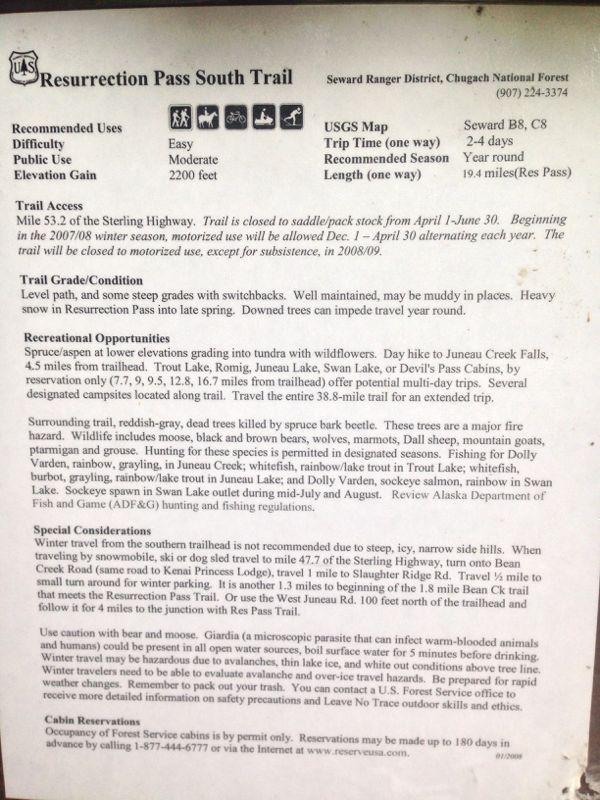 Alt text: Informational sign for the Resurrection Pass South Trail in the Chugach National Forest, detailing recommended uses, difficulty, elevation gain, trail access, conditions, recreational opportunities, special considerations, and contact information for cabin reservations. The sign outlines the trail's features and seasonal restrictions. Resurrection Pass mountain bike trail.