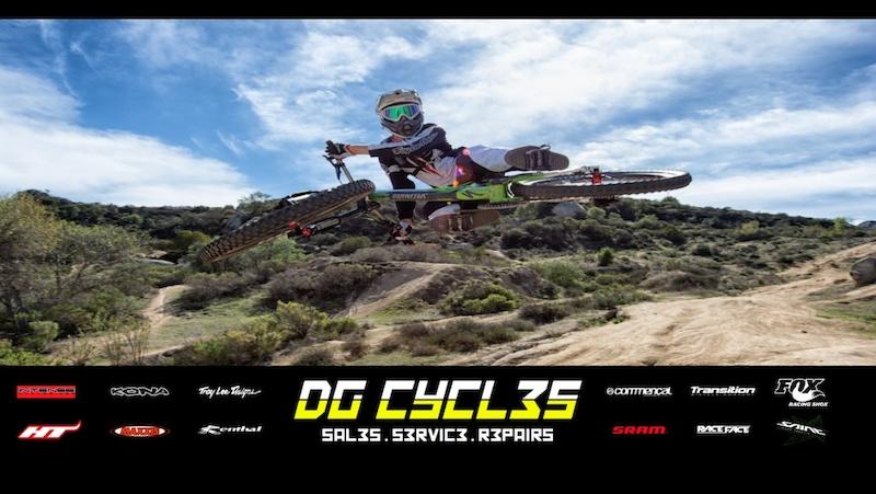 A mountain biker performing a mid-air jump over a dirt trail, with greenery and hills in the background. The image features the text "DG CYCL35" at the bottom along with various logos from cycling brands.