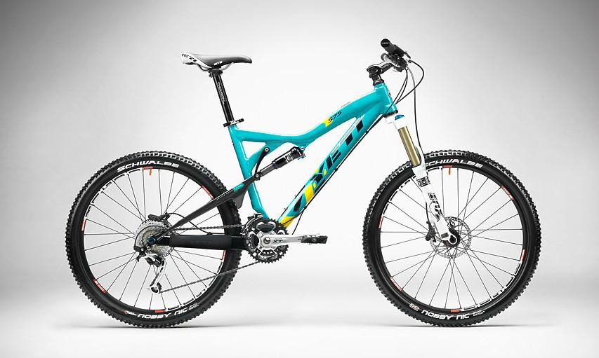 Yeti 575: A turquoise mountain bike with a lightweight frame, featuring dual suspension, wide tires, and disc brakes, positioned against a neutral gray background.