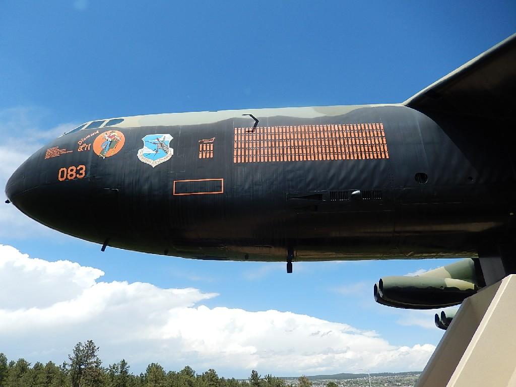 Alt text: Close-up view of the nose of a military aircraft with distinctive markings, including a numerical designation and squadron insignia, set against a partly cloudy blue sky. Falcon Trail mountain bike trail.