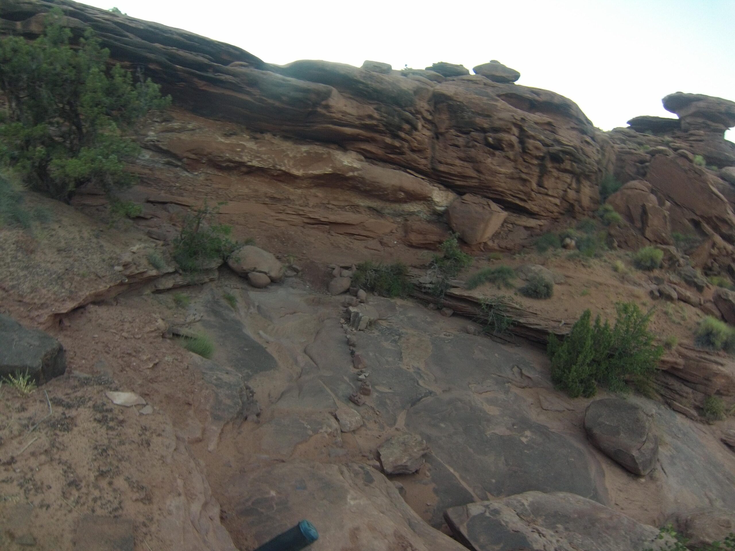 Rocky terrain with layered sandstone formations, sparse vegetation, and scattered boulders under a clear sky. Captain Ahab mountain bike trail.