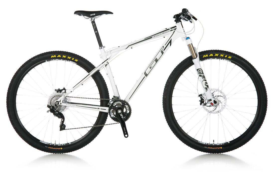 GT Zasker 9R Pro: Mountain bike with a white frame, featuring front suspension and black tires with yellow "MAXXIS" branding. The bike is equipped with multiple gears and a disc brake system, showcasing a sleek design suitable for outdoor riding.