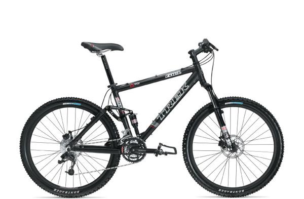 A black mountain bike with a sturdy frame and thick tires, featuring disc brakes and a suspension system, positioned against a white background. The bike is branded with the "Trek" logo.