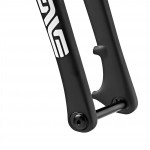 Close-up image of a black bike fork featuring a logo on the side, highlighting the design and mounting area. The background is plain white, emphasizing the fork's sleek lines and structure.