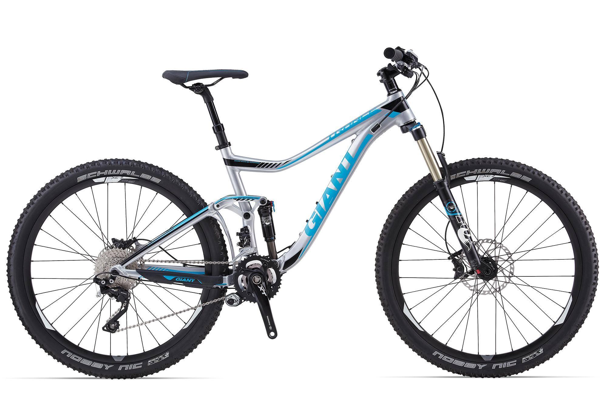 Giant Trance 27.5 1: A silver and blue mountain bike with large tires, front suspension, and a sleek frame design, positioned on a white background. The bike features a dropper seat post, disc brakes, and is equipped with Schwalbe tires.