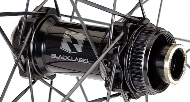Close-up of a black bicycle hub with the "BLACK LABEL" logo. The hub is surrounded by thin spokes, showcasing its intricate design and construction.