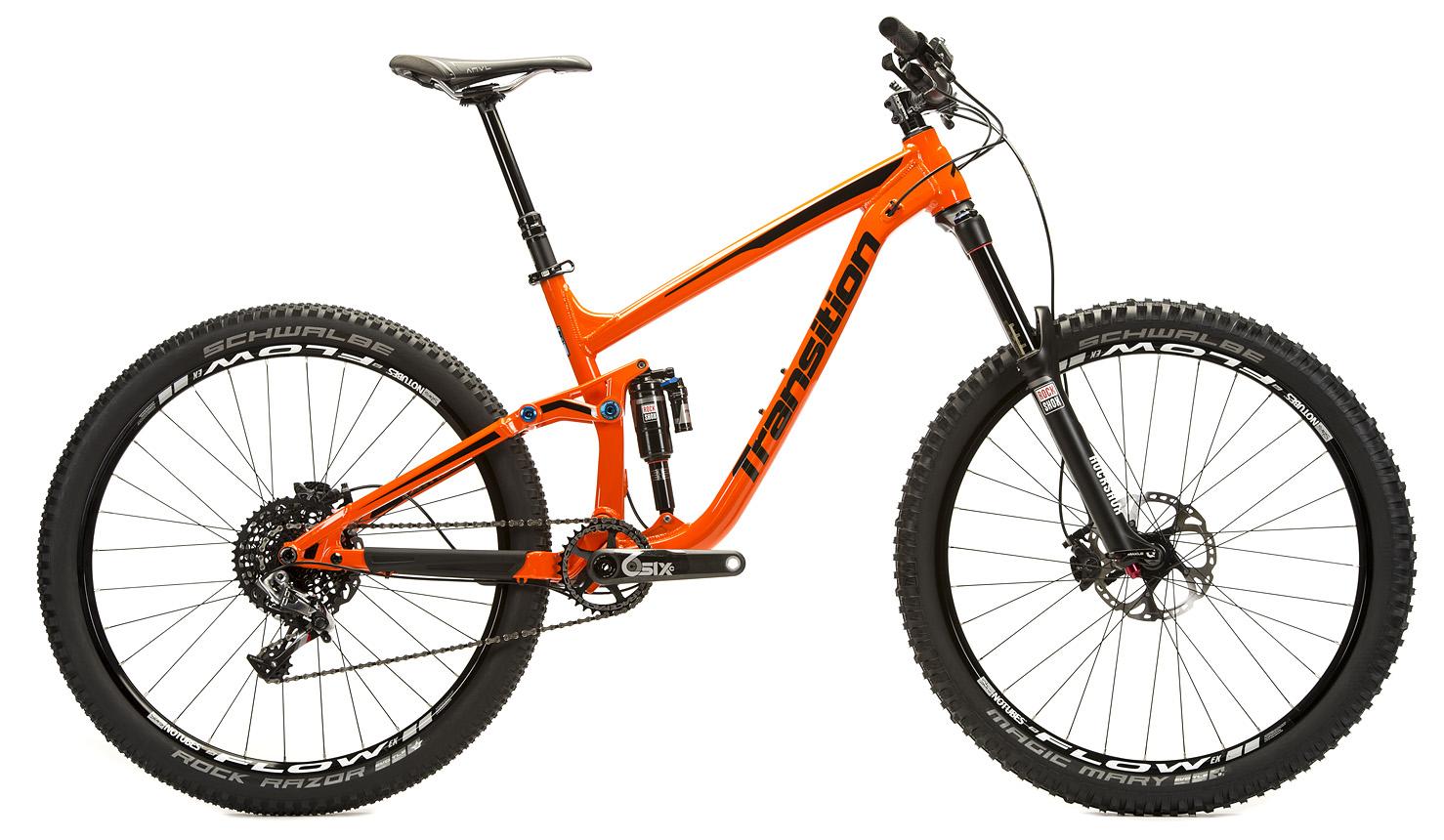 Transition Patrol: A vibrant orange mountain bike with a sturdy frame, featuring wide tires, disc brakes, and a rear shock. The bike is displayed against a white background, showcasing its sleek design and high-performance components.