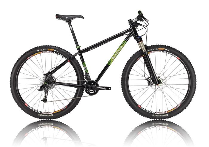 Salsa El Mariachi: A black mountain bike with green accents, featuring large, rugged tires and a sleek frame design. The bike is positioned on a reflective surface, showcasing its front suspension fork, drivetrain, and handlebars.